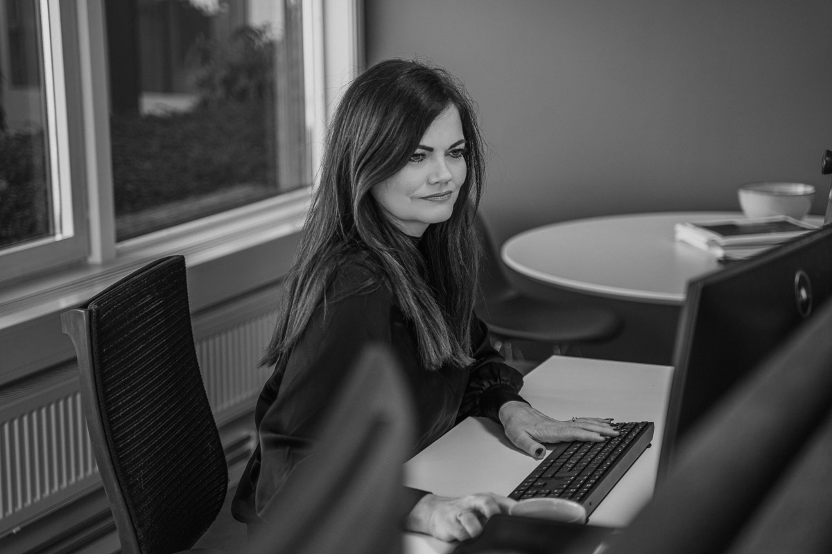 En sofistikert kvinne arbeider ved et skrivebord med en datamaskin, omgitt av luksuriøse detaljer og en kreativ atmosfære.