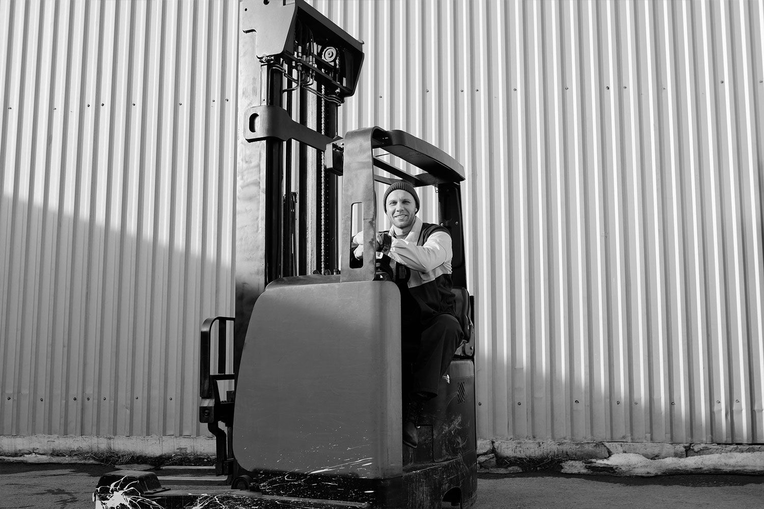 En sofistikert mann poserer på en gaffeltruck, med en imponerende bygning som bakgrunn, som utstråler moderne eleganse.