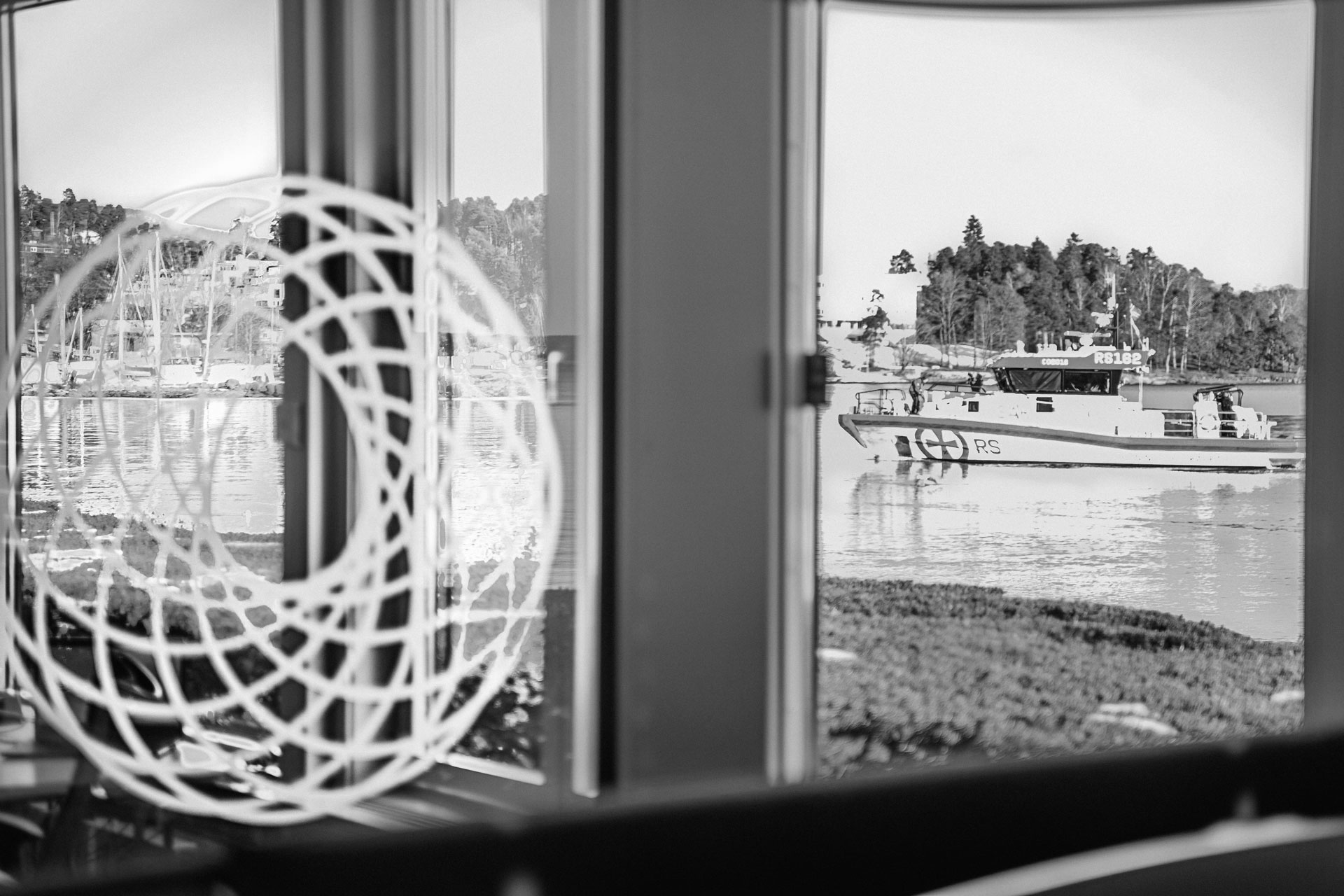 En stilfull svart-hvitt fotografi av en båt som glir majestetisk over vannflaten, innhyllet i ro og eleganse.