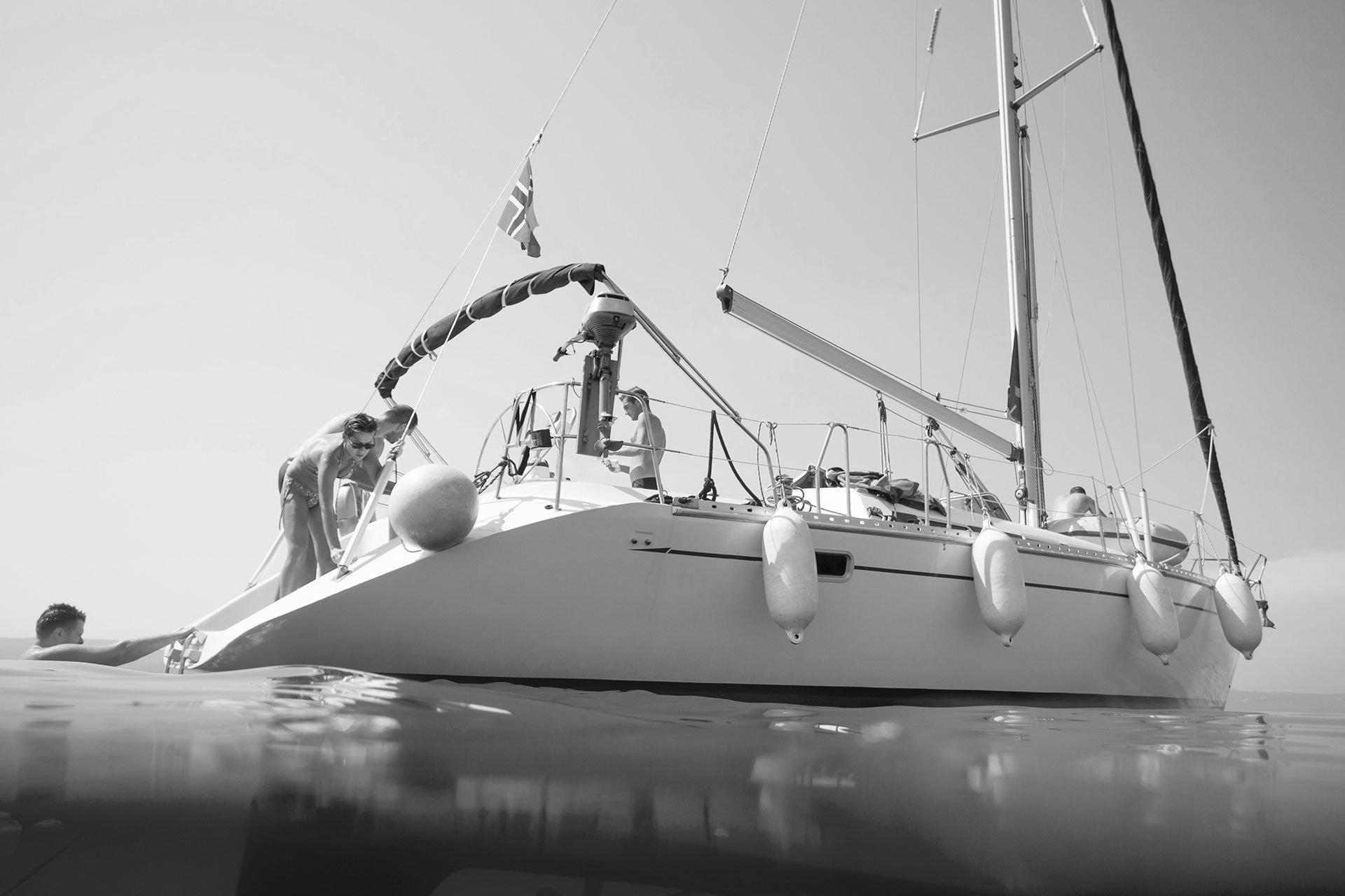Et svart-hvitt bilde av en seilbåt som elegant glir over vannflaten, omfavnet av ro og stillhet.