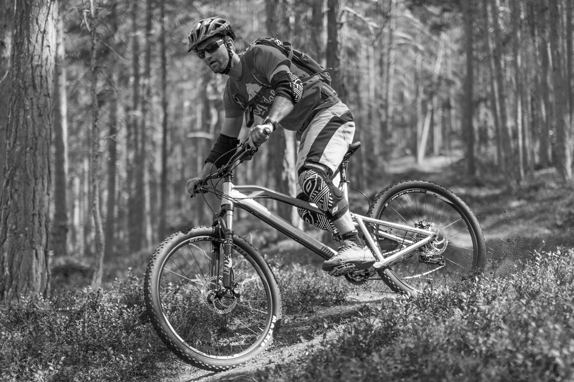 En svart-hvitt foto av en syklist som elegant navigerer gjennom naturskjønne stier.