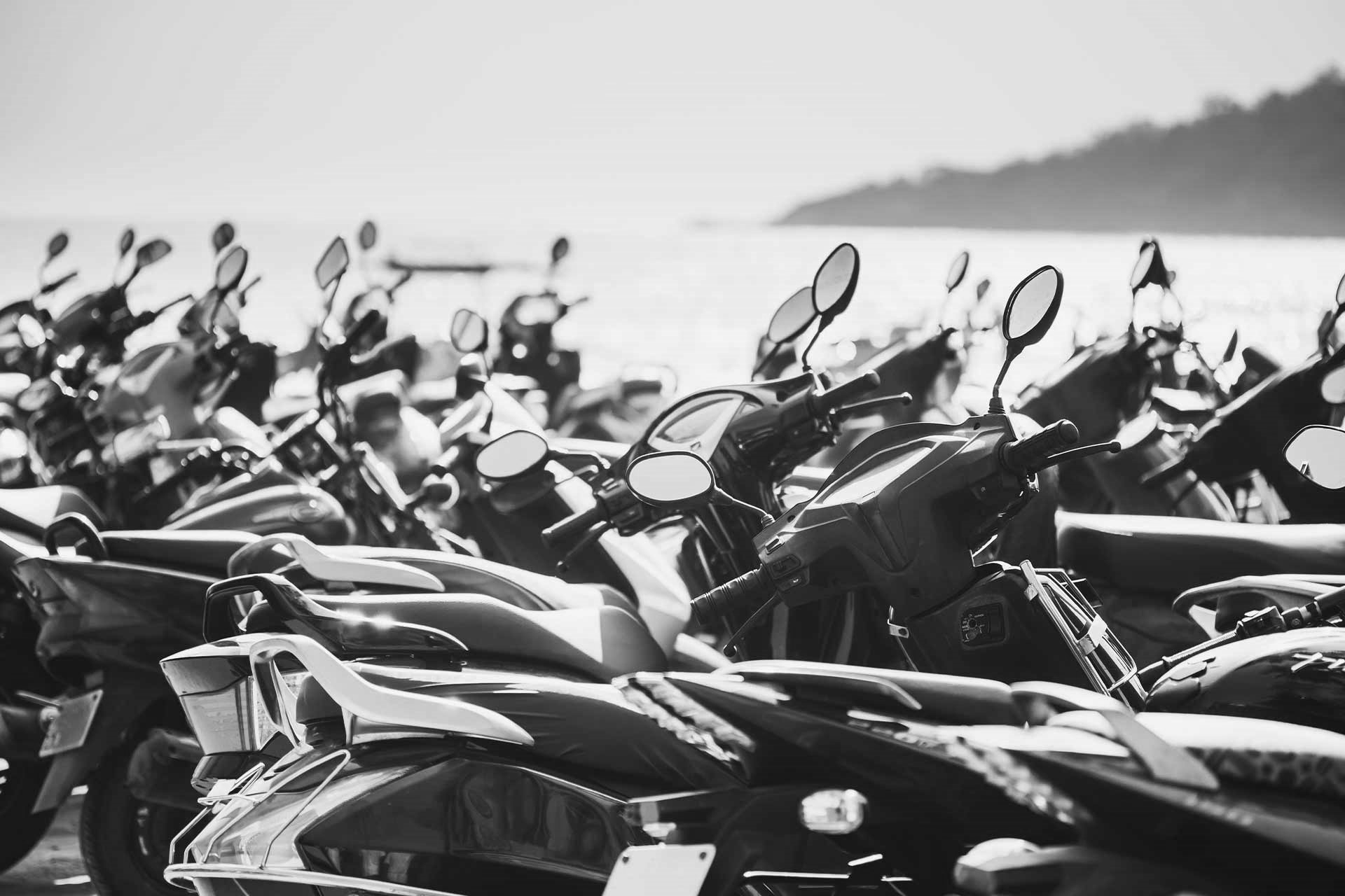 En elegant rad av motorsykler parkert langs stranden, som utstråler stil og frihet i et urbant landskap.