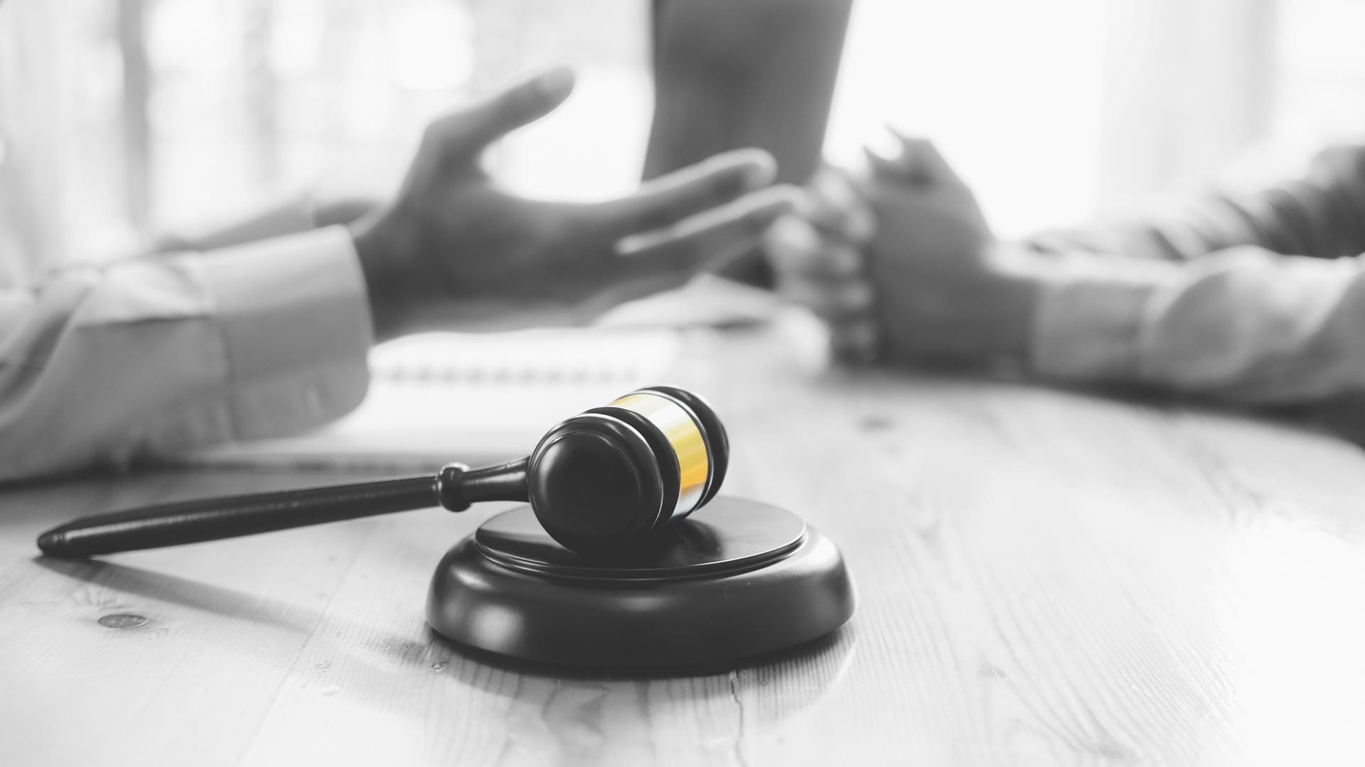 Svart-hvitt bilde av en dommerhammer plassert på et elegant bord, symboliserer rettferdighet og autoritet.